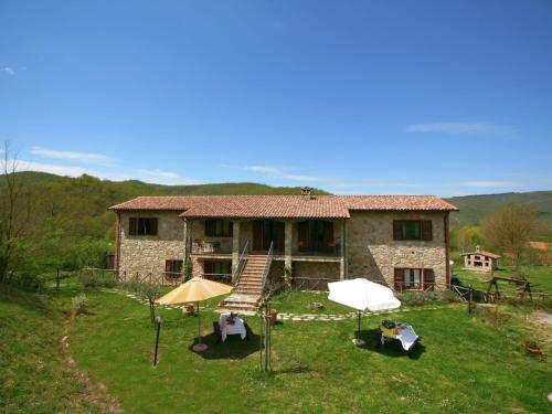 a stone house with two umbrellas in front of it at Farmhouse with small lake swimming pool private terrace garden and sheep in Passignano sul Trasimeno