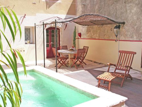 een patio met een tafel en stoelen naast een zwembad bij Attractive holiday home with swimming pool in Montagnac