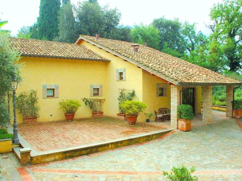una casa gialla con piante in vaso e un patio di Belvilla by OYO Montecorneo Monolocale a Perugia