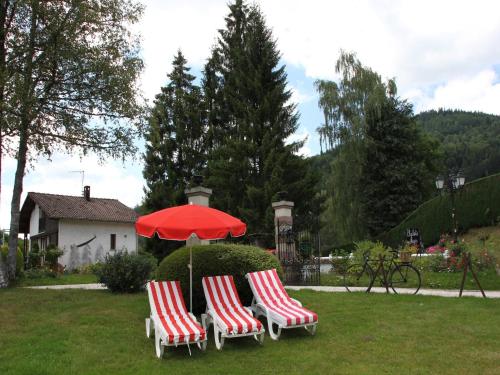 three red and white chairs and an umbrella in a yard at Chalet in France with Pool & Jacuzzi in Le Ménil