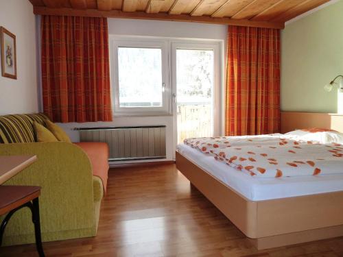 a bedroom with a bed and a couch and a window at Haus Arnika in Nauders