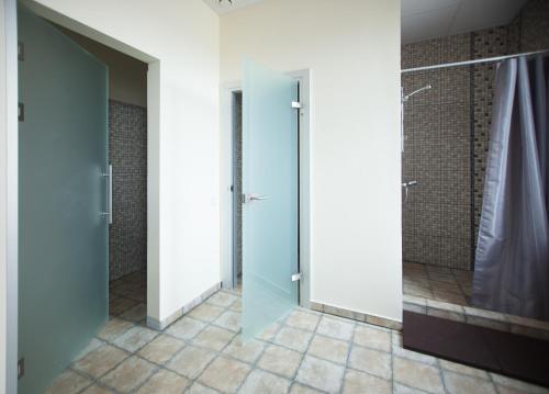 ein Bad mit einer ebenerdigen Dusche und einer Glastür in der Unterkunft SanMari in Daugavpils