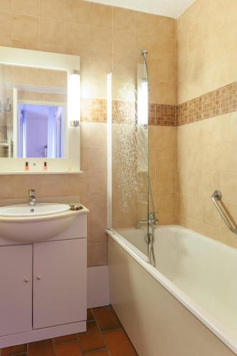 une salle de bain avec un lavabo, une baignoire et une douche dans l'établissement Résidence Pierre & Vacances Eden Parc, à Saint-Tropez