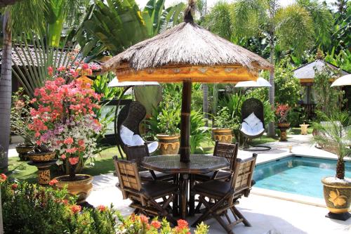 a table and chairs under a umbrella next to a pool at Villa Gusmania in Candidasa