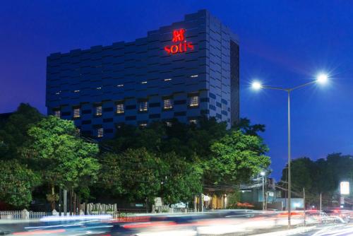a hotel with a lit up sign on top of a building at Sotis Residence Pejompongan in Jakarta