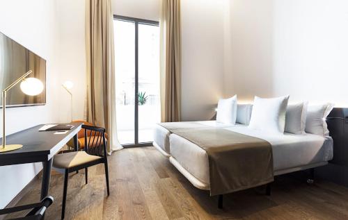 a hotel room with a bed and a desk and a window at One Shot Mercat in Valencia