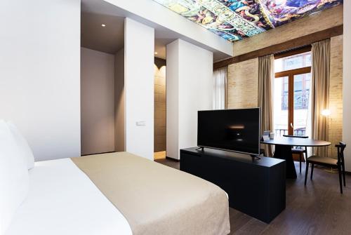 a bedroom with a bed and a tv and a table at One Shot Mercat in Valencia