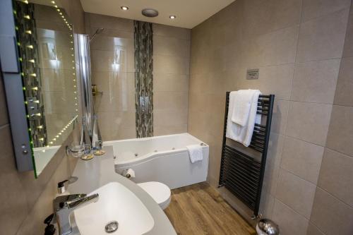 a bathroom with a tub and a sink and a toilet at The Upper House in Stoke on Trent
