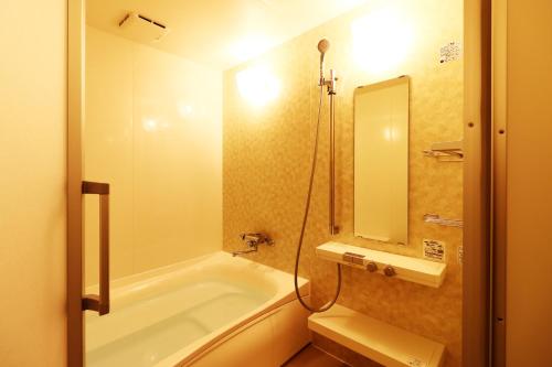 a bathroom with a tub and a sink and a mirror at Ryokan Karasawa in Kanazawa