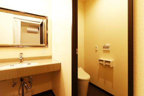 a bathroom with a sink and a mirror and a toilet at Ryokan Karasawa in Kanazawa