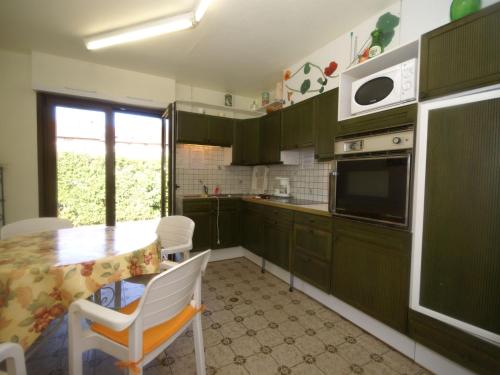 a kitchen with green cabinets and a table and a microwave at Holiday home in Vic sur Seille near the forest in Vic-sur-Seille
