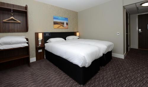 a hotel room with a large bed with white sheets at Mermaid, Ipswich by Marston's Inns in Ipswich