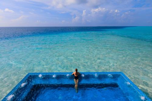 a man standing in the water in the ocean at Velassaru Maldives in South Male Atoll