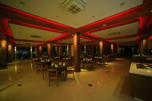 a dining room with tables and chairs and red lighting at Ruins Chaaya Hotel in Polonnaruwa