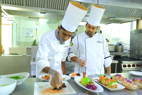 two chefs standing in a kitchen preparing food at Ruins Chaaya Hotel in Polonnaruwa