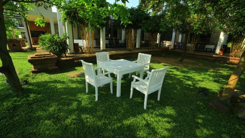 a white table and chairs in a yard at Ruins Chaaya Hotel in Polonnaruwa