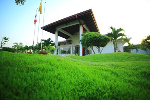 a building on top of a lush green field at Ruins Chaaya Hotel in Polonnaruwa