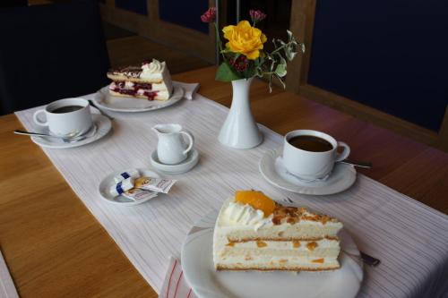 a table with a slice of cake and two cups of coffee at Hotel Seeterrassen in Laboe