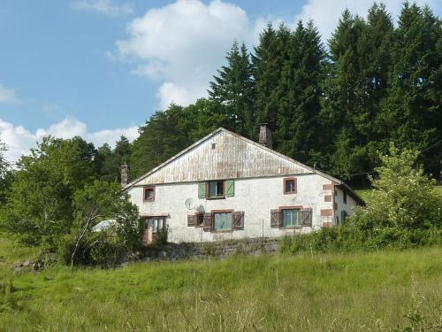 an old white house in a field with trees at Charming holiday home near the ski slopes in Vagney