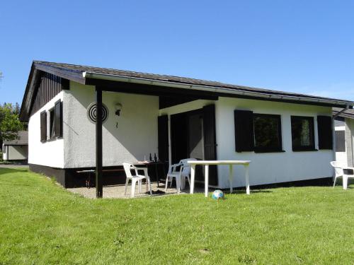 ein weißes Haus mit einem Tisch und Stühlen im Hof in der Unterkunft Cosy holiday home in Willingen Usseln with terrace in Willingen