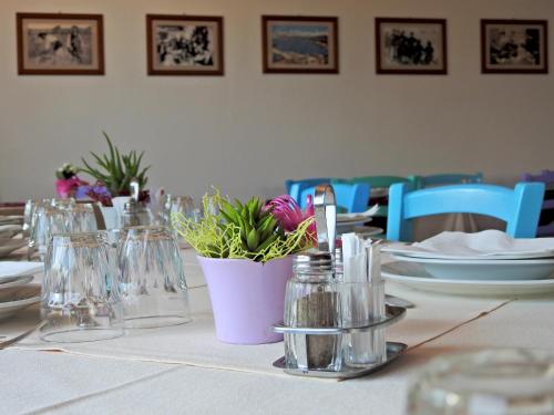 a table with a white table cloth with glasses and flowers at Agriturismo Codula Fuili in Cala Gonone