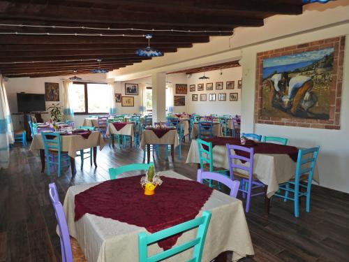a restaurant with tables and chairs and a painting on the wall at Agriturismo Codula Fuili in Cala Gonone