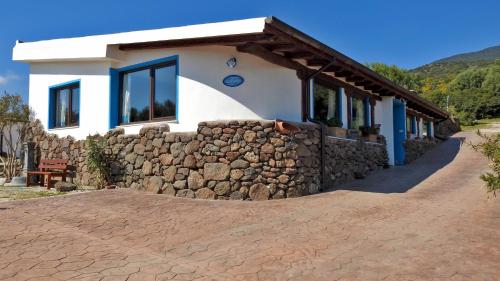 a house with a stone wall in front of it at Agriturismo Codula Fuili in Cala Gonone