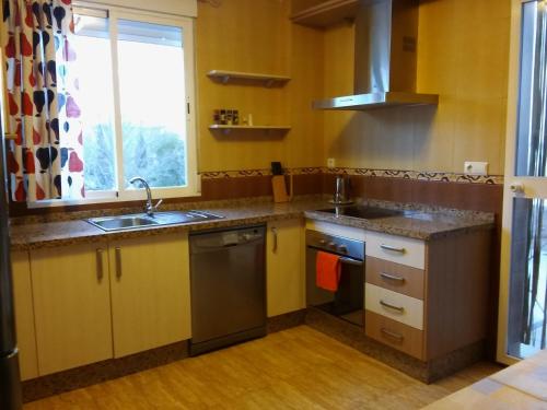 eine Küche mit gelben Schränken, einem Waschbecken und einem Fenster in der Unterkunft Casa Rural San Gines in Sabiote