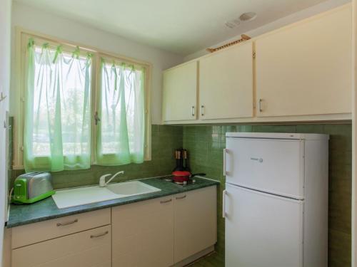 une cuisine avec des armoires blanches et un réfrigérateur blanc dans l'établissement Holiday Home in Cargèse near Beach, à Cargèse