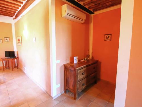 a room with an orange wall with a wooden dresser at Apartment in Montalto near Lake and Pool in Montalto di Castro