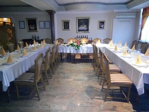 a room with long tables and chairs with white tablecloths at Business Club Selenča in Bač
