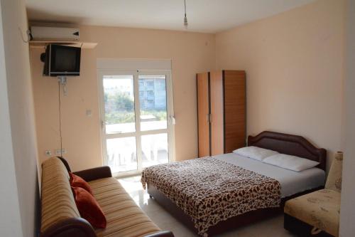 a bedroom with a bed and a couch and a window at Apartments Flamida in Ulcinj