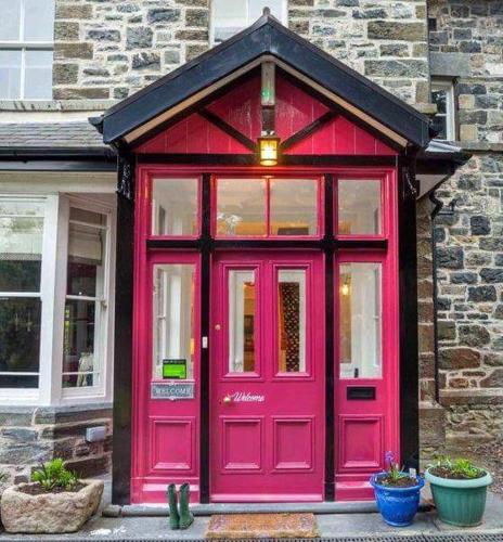 a red door on a brick building with windows at Summerhill Guest House in Betws-y-coed