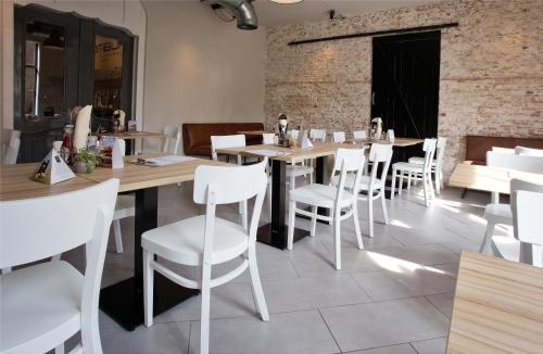a restaurant with wooden tables and white chairs at Studio's de Domburger in Domburg