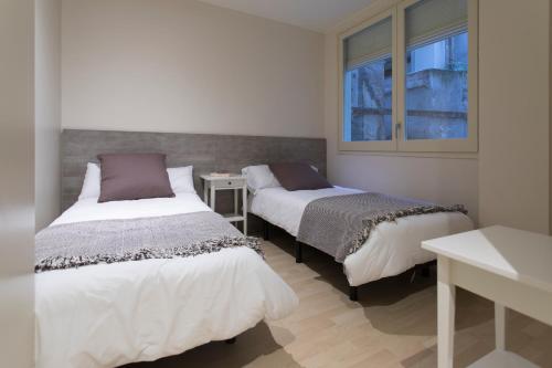 two beds in a room with a window at Bravissimo Cort Reial-3A in Girona