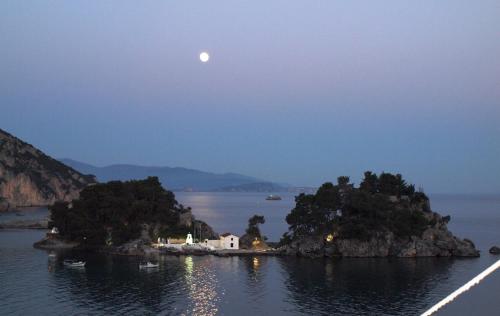 een maan boven een klein eiland in het water bij Sunrise House in Parga