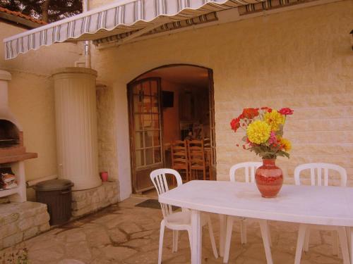 a white table with a vase of flowers on it at Cozy Cottage in Vaires sur Marne with Garden in Chelles