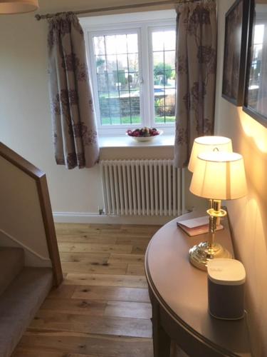 a room with a table with a lamp and a window at Scalby Grove Cottage in Scalby
