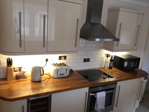 a kitchen with white cabinets and a wooden counter top at Scalby Grove Cottage in Scalby