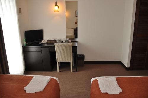 a hotel room with a desk and a table with a chair at Hotel Noah in Ginowan