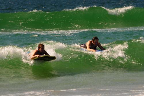 two people riding a wave on surfboards in the ocean at 3 Dolphins in Britannia Bay