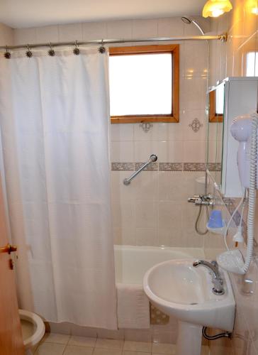a bathroom with a shower curtain and a sink at Patagonia Apart in Esquel