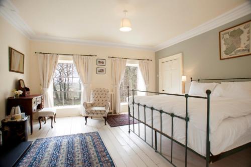 a bedroom with a bed and a chair and a window at Dromore House Historic Country house in Coleraine
