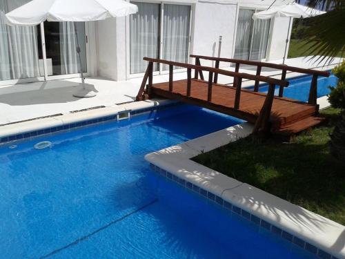 a blue swimming pool with a bench and umbrella at Punta del Este Arenas Hotel in Punta del Este