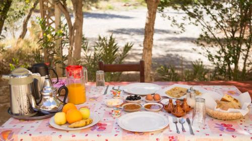 een tafel met borden eten en fruit erop bij Kasbah Hotel Camping Jurassique in Ifri