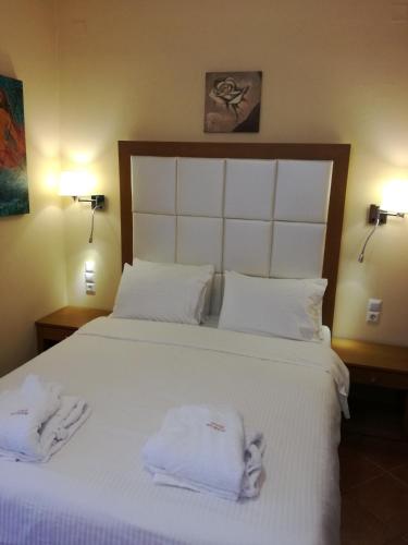a bedroom with a large white bed with towels on it at Petros Penthouse in Parga