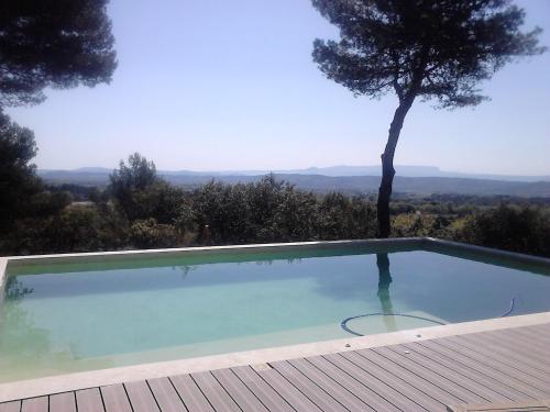 a swimming pool with a tree in the background at La Maison de Charlie in Vaugines