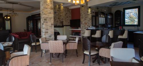 a restaurant with tables and chairs and a bar at Evzin Hotel in Kato Loutraki