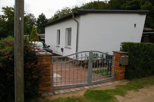 a metal gate in front of a white house at Ferienhaus Krüger in Loissin