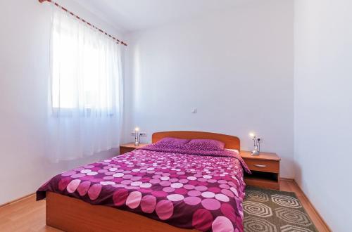 sypialnia z łóżkiem z fioletową kołdrą i oknem w obiekcie Apartments Andrej w mieście Zadar